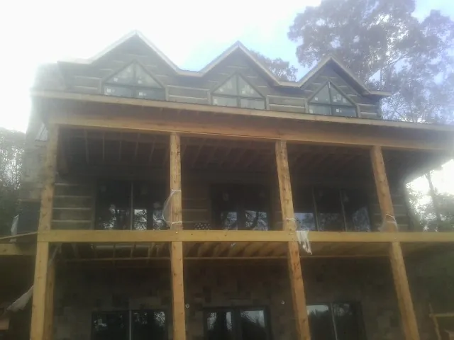 Dormers and porch framing on a large log home under construction — Roof Coating work by our crew in Fredericksburg